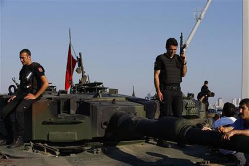 Turkish police officers loyal to the government stand atop tanks abandoned by Turkish army officers near Istanbul's iconic Bosporus Bridge Saturday