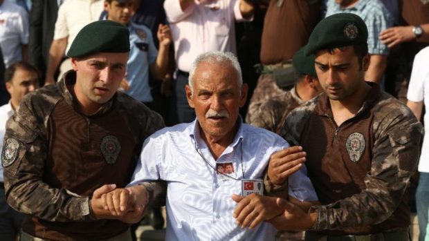 The father of a Turkish special forces policeman officer center is helped by two special forces policemen during his son's funeral procession in Ankara Turkey Wednesday