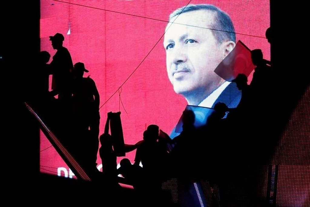 Turkish supporters silhouetted against a screen showing President Tayyip Erdogan during a pro-govt demonstration