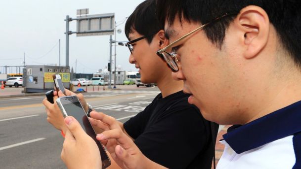 Two South Koreans play the Pokemon Go game with their mobile phones in Sokcho South Korea