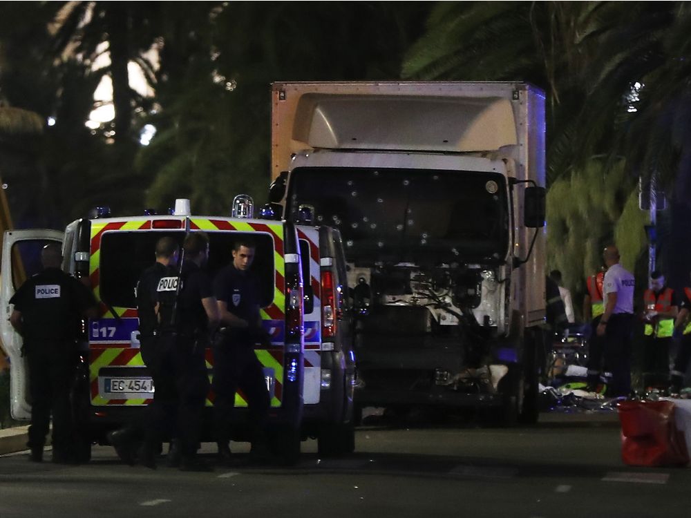 Police officers and rescued workers stand near a van that ploughed into a crowd leaving a fireworks display in the French Riviera town of Nice