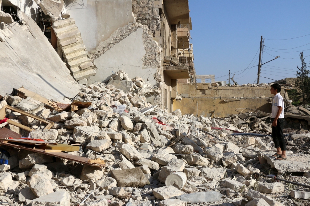 A young Syrian stands looking at the rubble of a collapsed building as rescuers look for victims the following a reported air strike on the rebel-held neighbourhood of Sakhur in the northern city of Aleppo