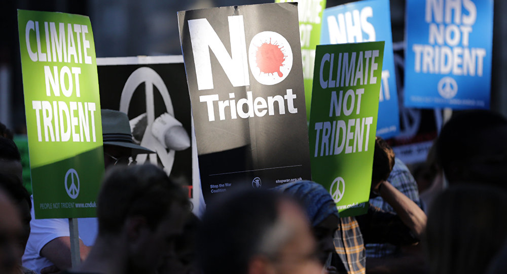 Demonstrators hold placards calling for government funds to be spent on the NHS and climate change as they attend an anti-war and anti-trident demonstration near the Houses of Parliament in central London