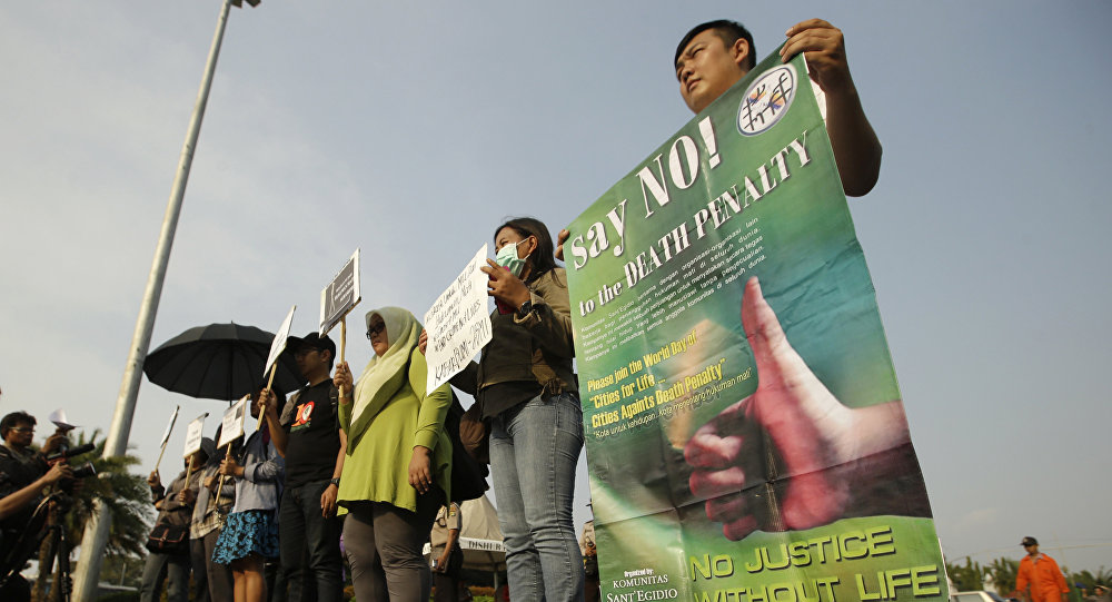 Protesters hold posters as they attend a rally against death penalty outside the presidential palace in Jakarta Indonesia Tuesday