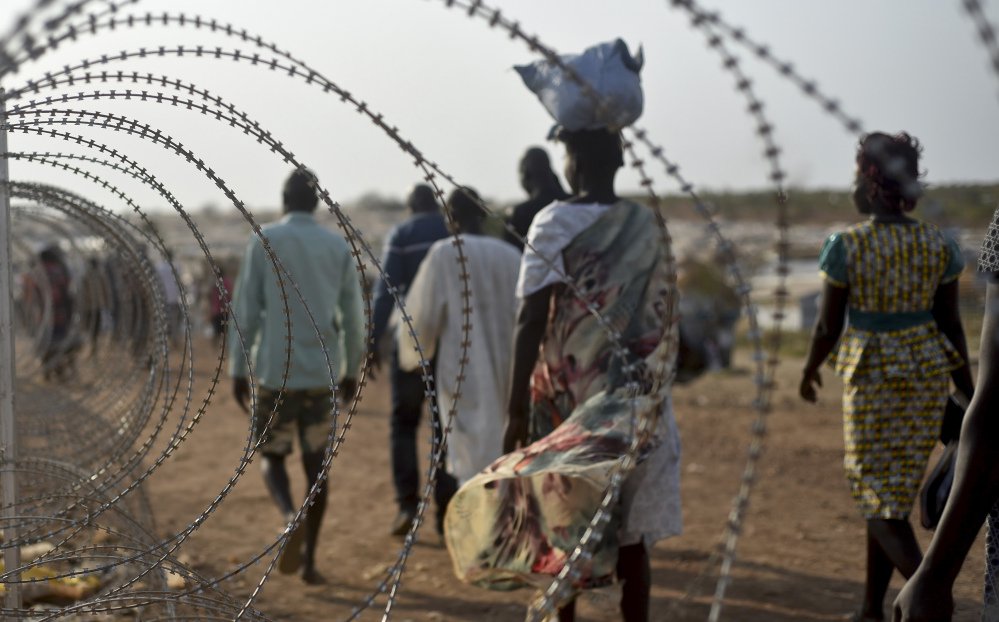 People walk next to a razor wire fence at the United Nations base in the Juba South Sudan last January. Ethnic Nuer women and girls were reportedly raped near here last week