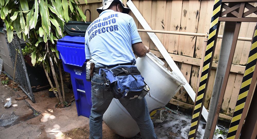 Miami-Dade mosquito control worker Carlos Vargas dumps a barrel of standing water that can incubate the Aedes aegypti mosquito larvae at a home in Miami Florida