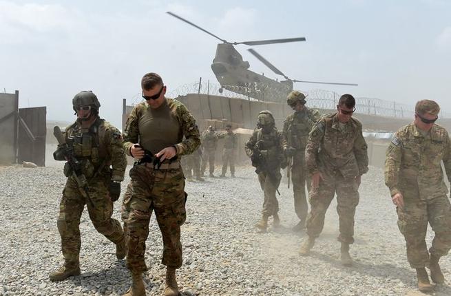 U.S. Army soldiers walk as a NATO helicopter flies overhead at coalition force Forward Operating Base Connelly in the Khogyani district in the eastern province of Nangarhar