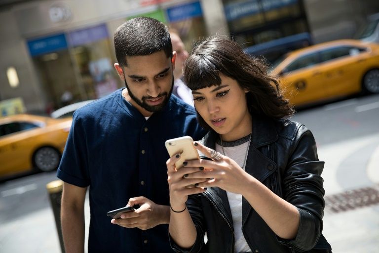 Sameer Uddin and Michelle Macias play Pokemon Go on their smartphones outside Nintendo's flagship store in New York