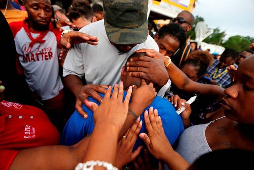 Cameron Sterling son of Alton Sterling is comforted by hands from the crowd at a vigil outside the Triple S convenience store in Baton Rouge La