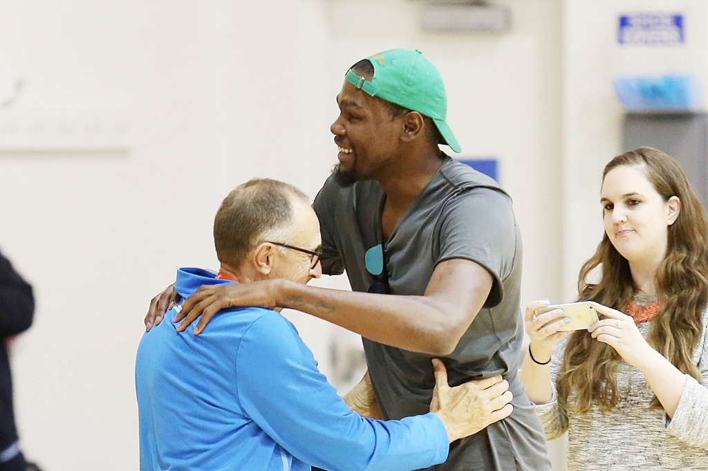 Kevin Durant embraces Golden State Warriors assistant coach Ron Adams before a news conference about Durant joining the Warriors at the NBA basketball team's practice facility Thursday