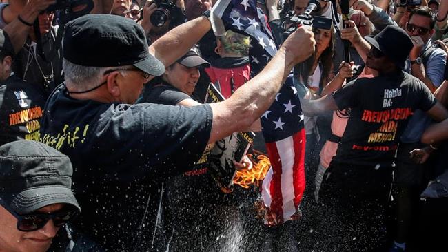 Supporters of the'Revolutionary Communist Party USA burn the US flag outside the gates of the Quicken Loans Arena the site for the Republican National Convention in Ohio