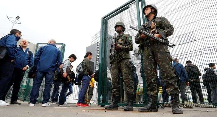 People queue at a security check to enter the main press center as Brazilian military police soldiers provide security at the 2016 Rio Olympics Park in Rio de Janeiro Brazil