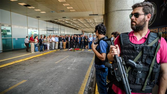 Turkish police officers stand guard as consuls of European countries lay cloves and roses at the explosion site at the Istanbul Ataturk Airport's International terminal