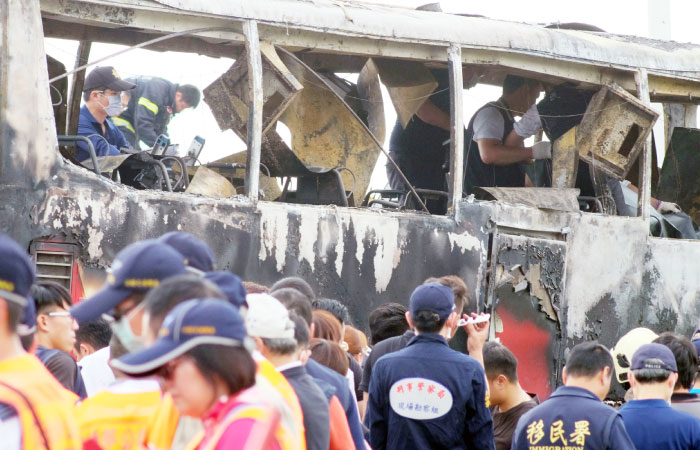 Investigators inspect a bus carrying tourists from mainland China that crashed and caught fire along an expressway on its way to the airport in Taiwan’s city of Taoyuan on Tuesday. — AFP