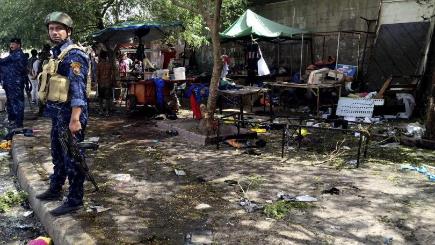 Iraqi security forces and civilians gather at the scene of a bomb in Kadhimiyah district Baghdad on Sunday July 24