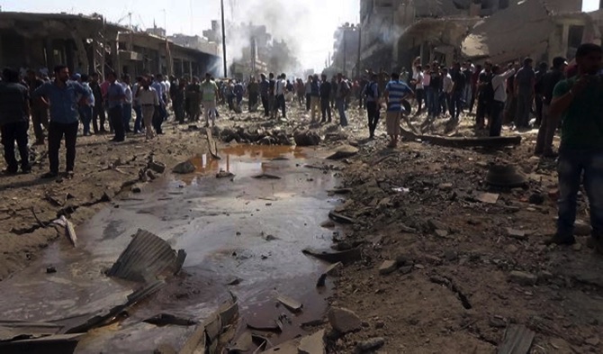 Syrian official news agency SANA Syrians gather at the scene where twin bombings struck Kurdish town of Qamishli yesterday