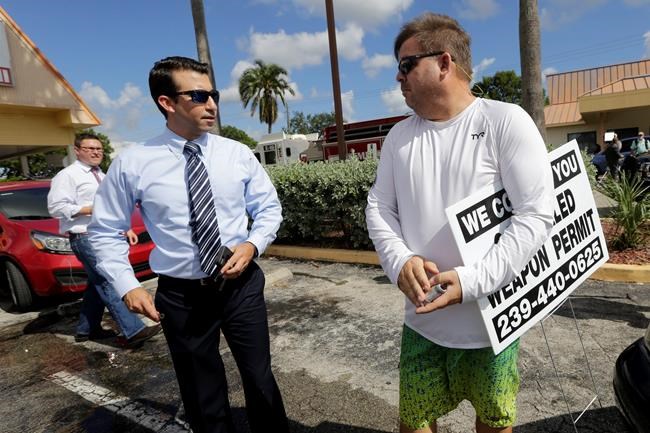 A man right talks with a member the news media and passes out information on how to obtain a concealed weapons permit outside the scene of a deadly shooting outside the Club Blu nightclub in Fort Myers Fla. Monday