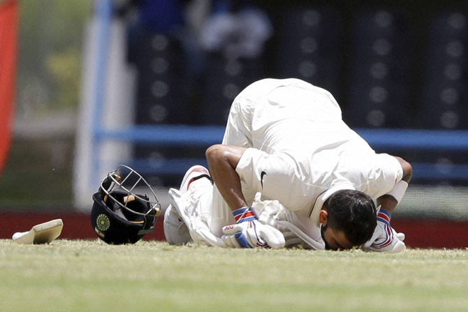 India's captain Virat Kohli kisses the field after scoring a double-century during day two of the first cricket Test match against West Indies at the Sir Vivian Richards Stadium in North Sound Antigua on Friday