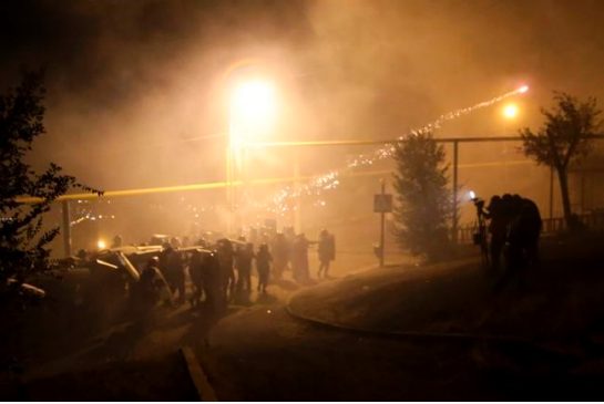 Riot police use light grenades as they confront anti-government protesters supporters of the armed group who have been holed inside a police station clash with police in Yerevan Armenia Friday