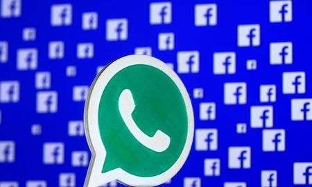 A 3D printed Whatsapp logo is seen in front of a displayed Facebook logo in this illustration taken