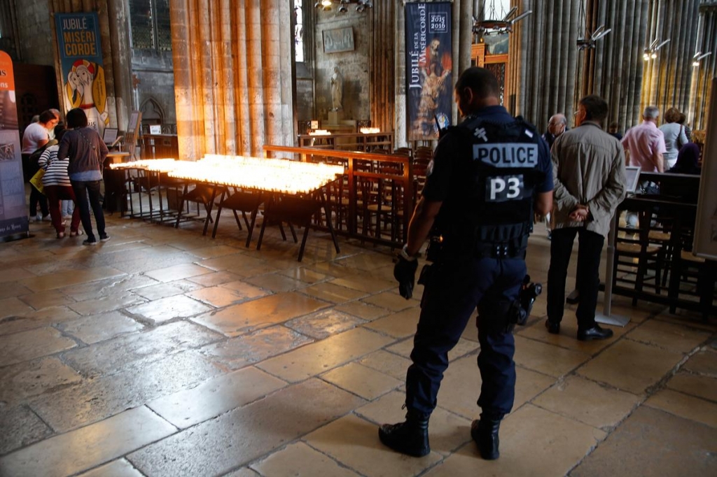 A French policeman stands guard as people attend a mass to pay tribute to French priest Father Jacques Hamel