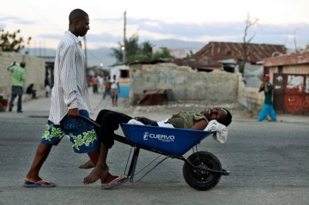 A Haitian with symptoms of cholera is transported in a wheelbarrow in Port-au Prince   Thomson Reuters