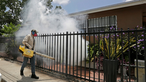 A Miami Dade County mosquito control worker sprays around a home Aug. 1 in the Wynwood area of Miami