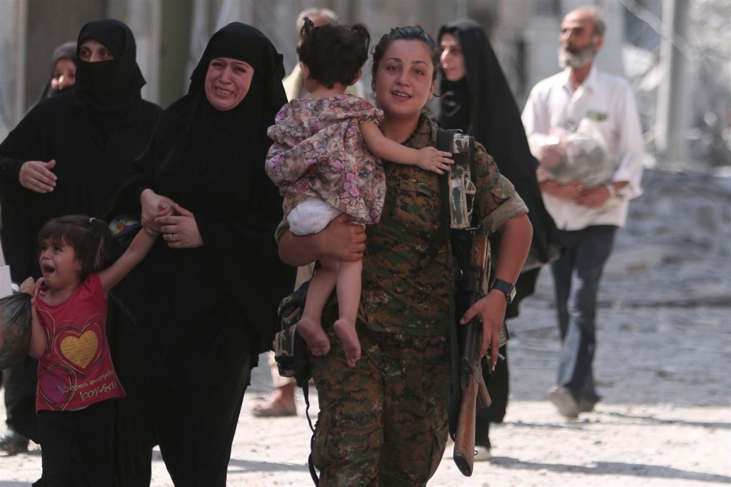 Image A Syria Democratic Forces fighter helps civilians who were evacuated from an ISIS-contolled part of Manbij in northern Syria