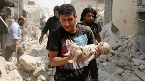 A Syrian man carries a dead baby after a barrel bomb attack on the Bab al Nairab neighborhood