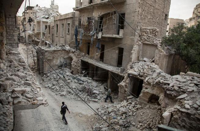 A Syrian man walks past destroyed buildings