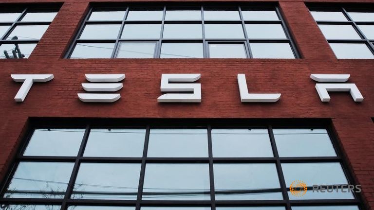 A Tesla logo hang on a building outside of a Tesla dealership in New York U.S