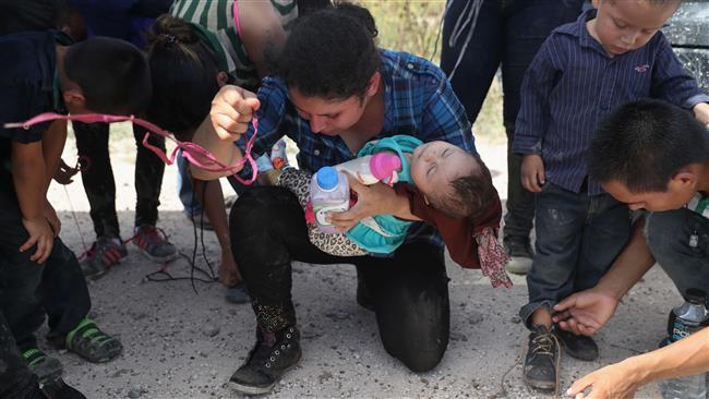 Immigrants from Central America remove the shoe laces from their shoes while being detained by US Border Patrol