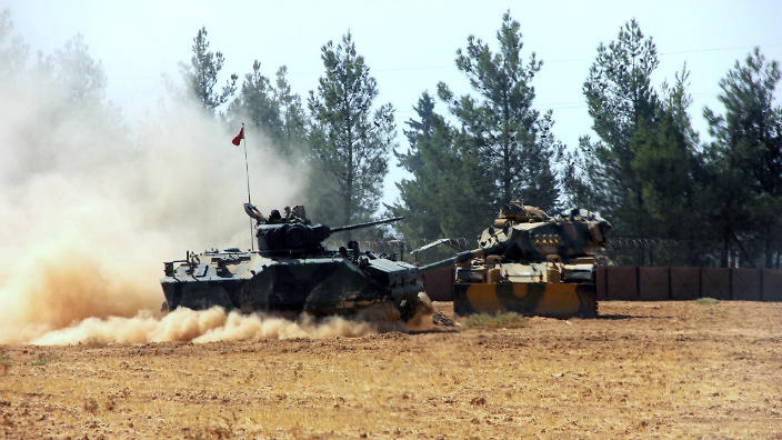 A Turkish army tank and an armoured vehicle are stationed near the border with Syria