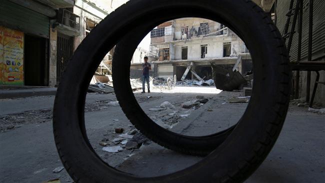 A boy walks past damaged shops and buildings in a militant-held area of Aleppo Syria