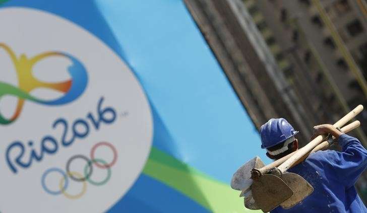 A construction worker walks by a logo of the Rio 2016 Olympics in Rio de Janeiro Brazil