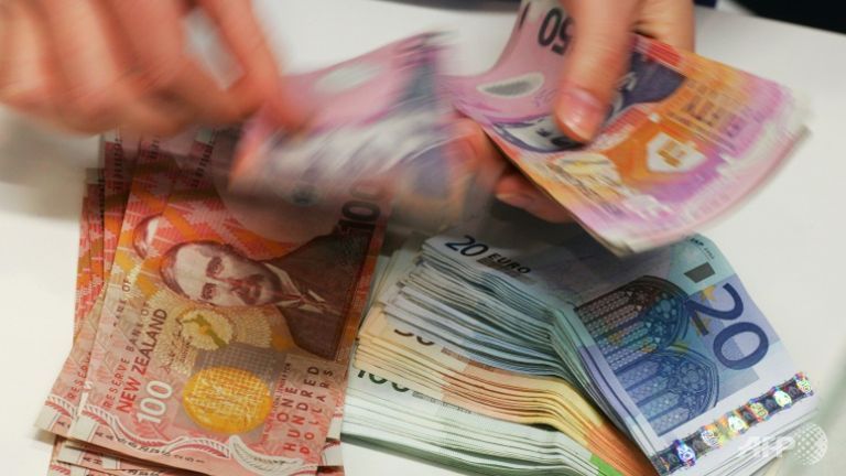 A currency exchange teller counts out New Zealand dollars alongside a stack of Euros in Auckland.
   
 

  Enlarge  Caption