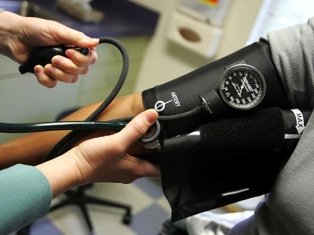 A doctor reads a blood pressure gauge during an examination of a patient