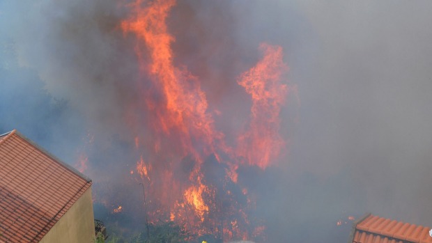 A firefighter works to stop a forest fire from reaching houses on the outskirts of Funchal