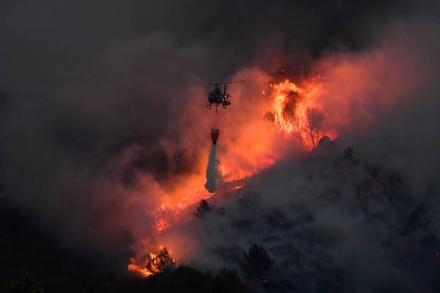 A helicopter carries an extinguisher in the struggle against a spreading fire near Vitrolles southern France