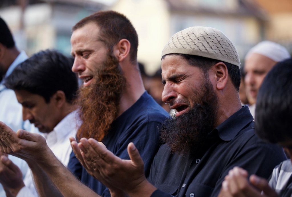 A man cries as others offer prayers on a road as a protest in Srinagar against the recent killings in Kashmir