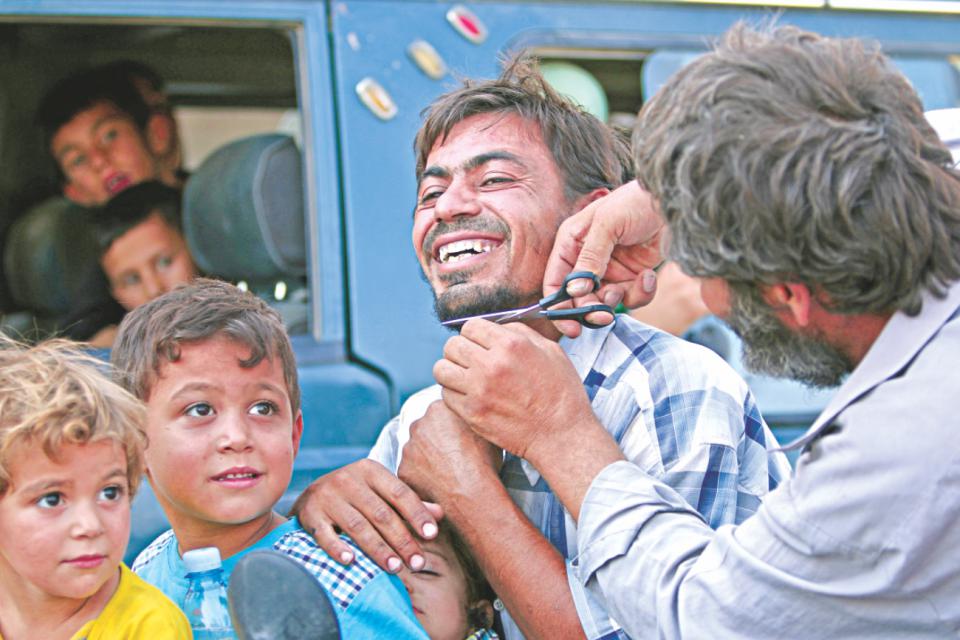 A man cuts the beard of a civilian women run with newborn babies