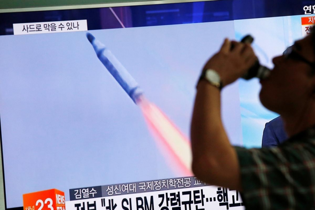 A man in Seoul walks past a TV screen broadcasting a news report on North Korea's submarine-launched ballistic missile