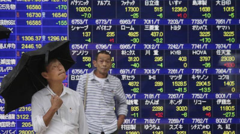 A man looks up at the sky in front of an electronic stock indicator of a securities firm in Tokyo