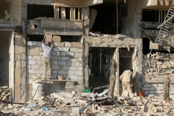 A man rebuilds a wall of a damaged building in the rebel held al Katerji district in Aleppo Syria