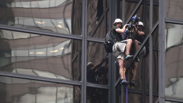 A man scales the all-glass facade of Trump Tower using suction cups