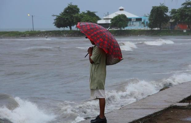 A man shields from the rain with an umbrella as Hurricane Earl passes the coast of La Ceiba Honduras