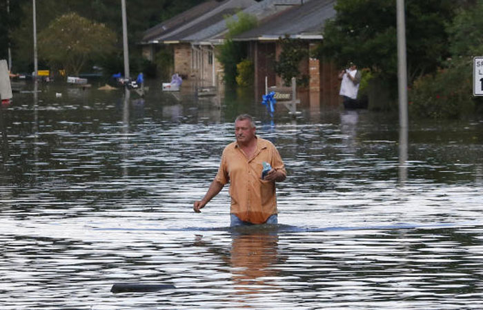 A man wades through a flooded street in Ascension Parish Louisiana on Monday. — Reuters