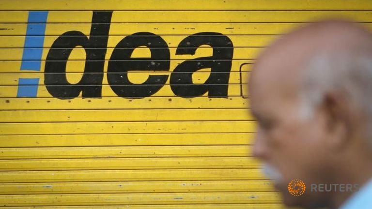 A man walks past a shop displaying Idea Cellular Ltd's logo on its shutters in Mumbai