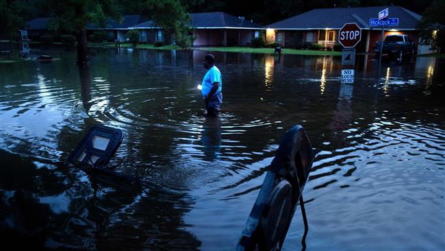 A man walks to his house through a flooded neighborhood in Baton Rouge Louisiana