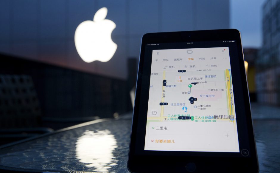 A mobile device displaying the Didi Chuxing app is posed near the Apple store logo in Beijing China. Pic AP